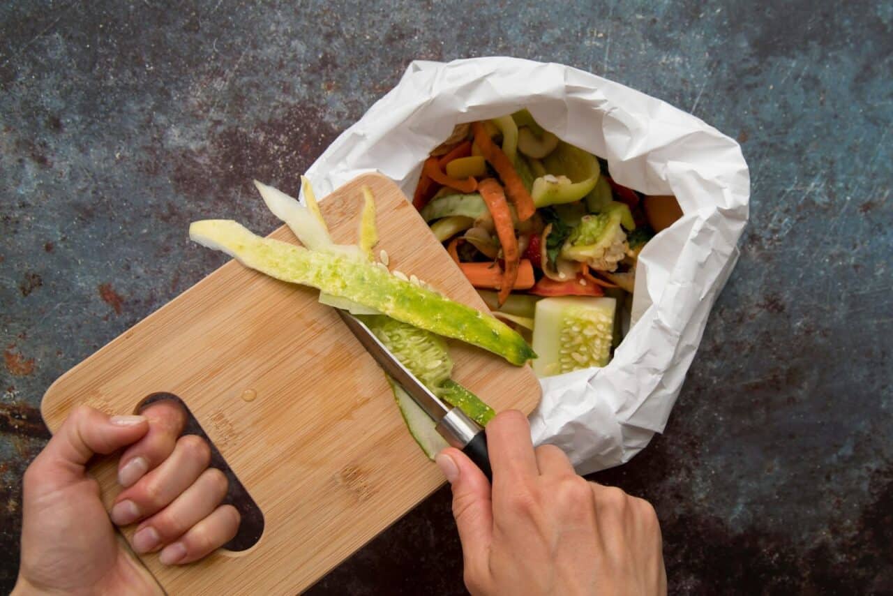 vegetables being disposed into a plastic bag after being sliced for cooking