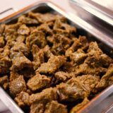 A stainless steel catering chafing dish filled with a large batch of slow-cooked Beef Rendang, ready for buffet service.